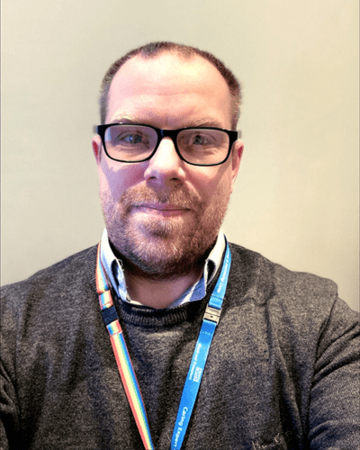 Matthew wearing an NHSBT lanyard and smiling at the camera
